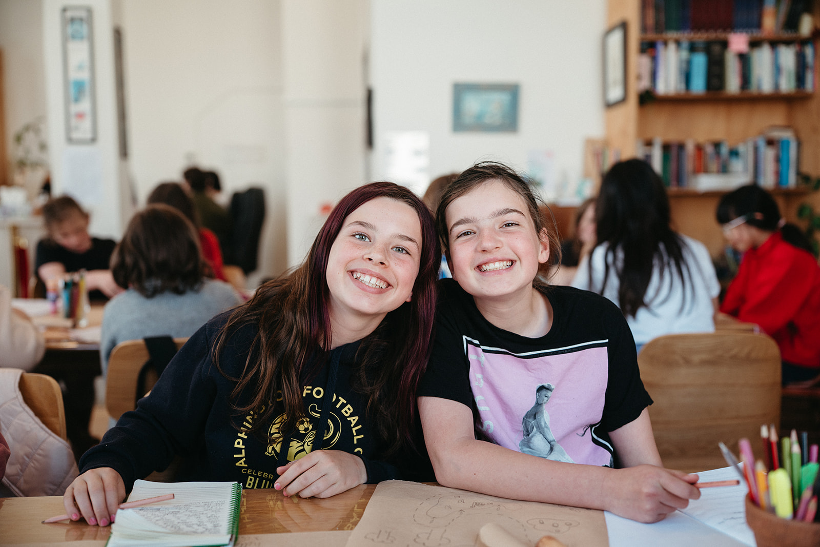 Two young writers smiling together with their notebooks